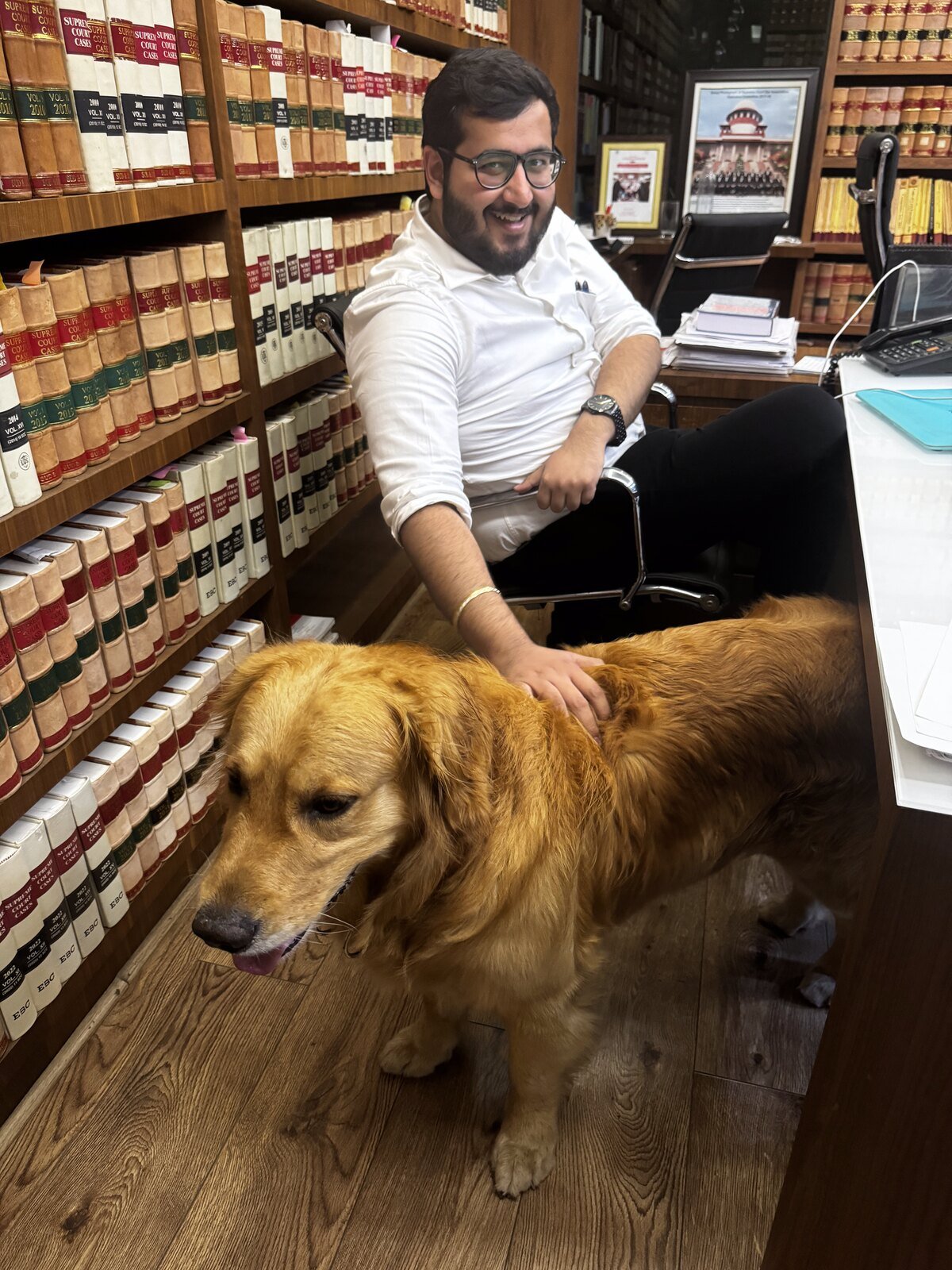 Shivam Nagpal in his chambers, surrounded by Supreme Court Cases volumes, with his golden retriever